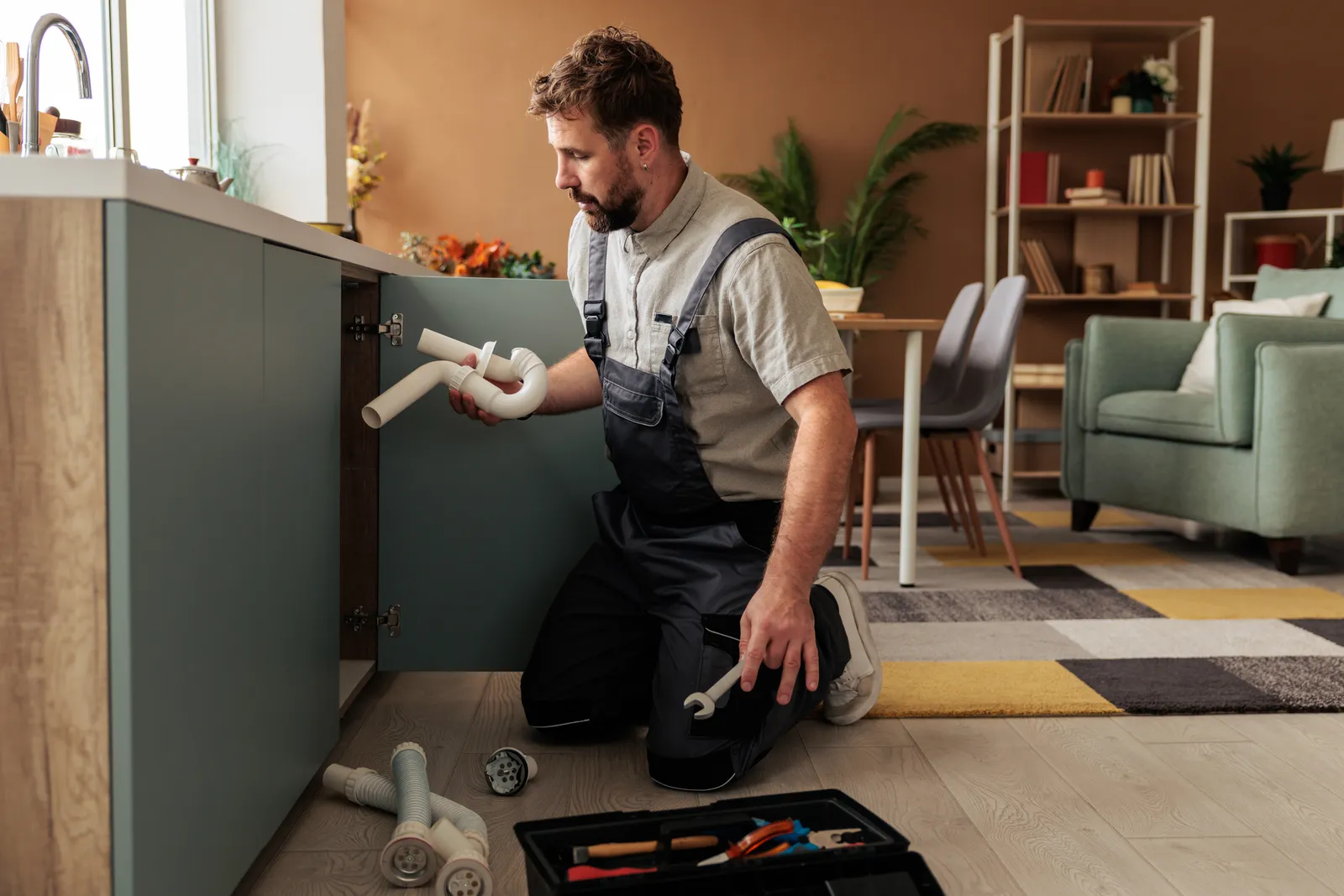 Plumber repairing a drain under a kitchen sink